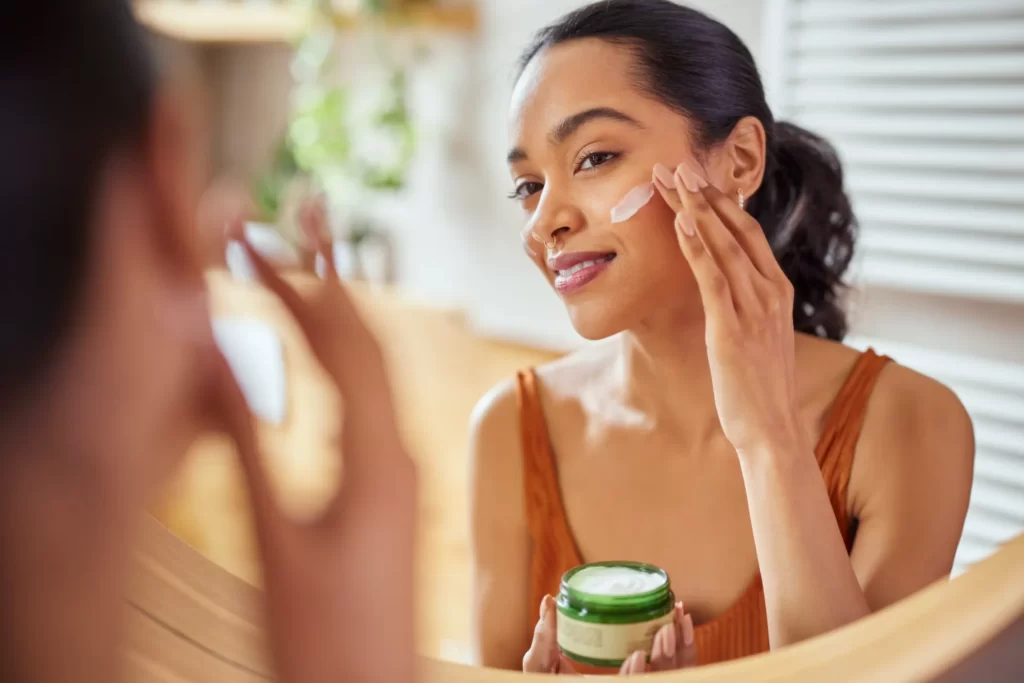 attractive woman applying cream to her face utc