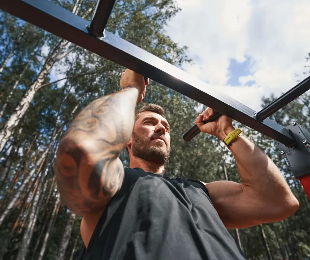 bearded man does pull ups outdoors utc