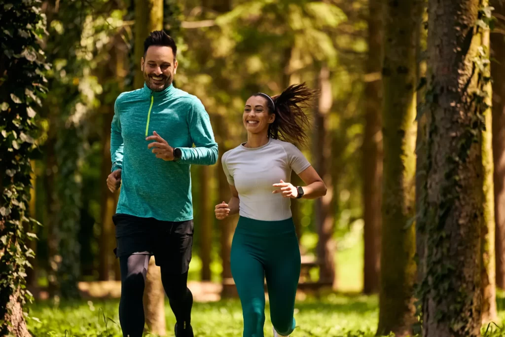 happy couple jogging together through a forest utc